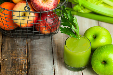 Healthy food, vegan diet concept - glass of fresh green juice or smoothie with celery, apple, orange. Antioxidant fresh detox beverage with raw ingredients.  Close up, wooden background, copy space