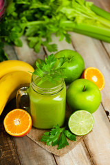 Healthy eating, food and vegetarian diet concept - mason jar of fresh juice or smoothie with apple, celery, orange. Antioxidant detox beverage. Clean organic ingerdients. Close up, wooden background