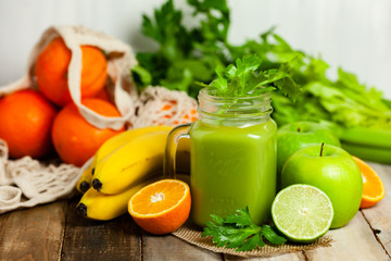 Green delicious smoothie made with apple, celery, lime, banana. Healthy eating, food and vegetarian diet concept. Antioxidant detox beverage. Clean organic ingerdients. Close up, wooden background.