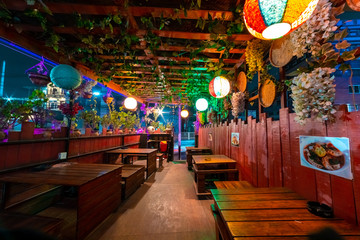Interior of a cafe restaurant decorated with plants and chinese lanterns at night