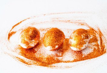 Obraz premium Easter eggs decorated with golden spangles on white background. Festive concept, minimalism. Close-up