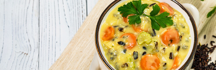 Cream of Chicken and Wild Rice Soup on White Wooden Background. Homemade Fresh Creamy Soup with Chicken, Carrot, Vegetables and Wild Rice. Selective focus.