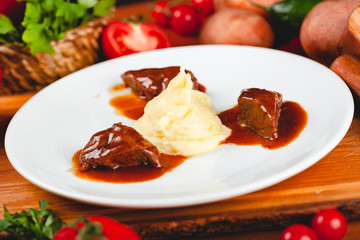 Fried meat pieces served with mashed potato garnish on white plate.