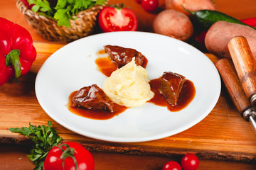 Fried meat pieces served with mashed potato garnish on white plate.