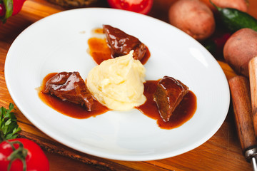 Fried meat pieces served with mashed potato garnish on white plate.