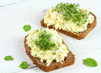 Egg salad over brown bread with garden cress. White background.  Homemade spread made from eggs,...