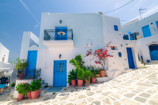Amazing narrow streets of popular destination on Paros island. Greece. Traditional architecture and colors of mediterranean city. Blue doors, white buildings and bougainvillea flowers in paradise