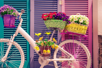 Fototapeta na wymiar Abstract colorful decoration with painted vintage bicycle and baskets with fresh flowers