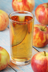 A glass with apple juice and ripe apples	