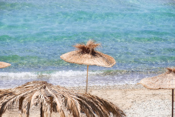 Abstract view  of amazing beach landscape with straw umbrella near azure sea. Mediterranean...