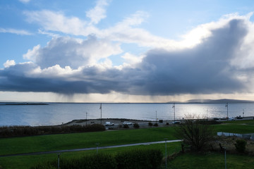 Obraz premium Rain clouds pouring over the ocean with blue sky. Taken on Salthill promenade in Galway, Ireland