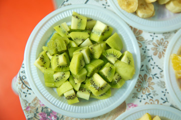 Cut kiwi in a plastic bowl. Banana slices in bowl over stone background with copy space. Healthy natural vitamin snack. Top view, flat . The chopped kiwi is in a plastic bowl .