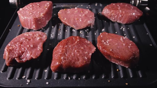 Delicious juicy meat steak cooking on grill. Aged prime rare roast grilling tenderloin fresh marble tenderness beef. Prime beef fry and pour salt, rosemary, black pepper in slow motion.