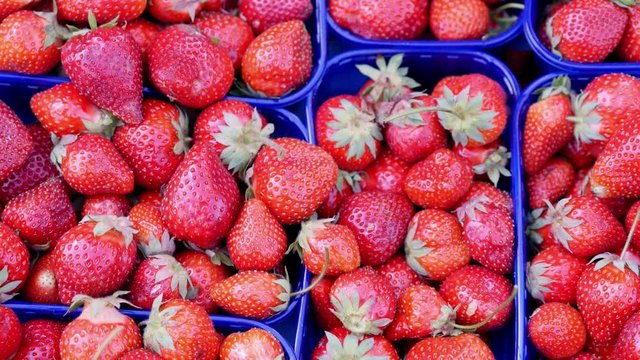 Footage at a fruits and vegetables market baskets of strawberries lying on a table, the shot comes into focus and goes OOF again...
