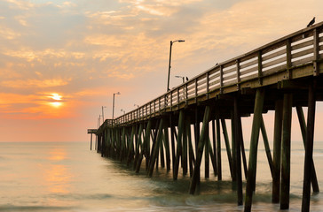 Fishing Pier at Sunrise at Virginia Beach, Virginia, USA. Virginia Beach, a coastal city in southeastern Virginia, lies where the Chesapeake Bay meets the Atlantic Ocean.