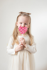 Portrait of little girl with heart candy on a stick, lollipops, copy space for text, Valentine's day, love, white background