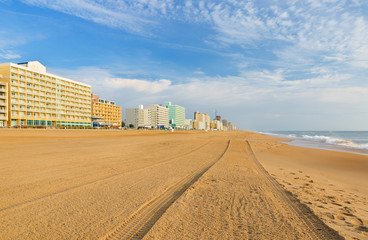 Virginia Beach at Sunrise. Photo shows hotels along the boardwalk and sand beach. The beach stretches three miles along the Atlantic ocean.