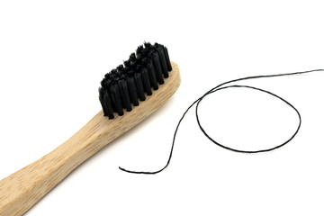 Close-up of black dental floss and black bamboo toothbrush. Close up, macro
