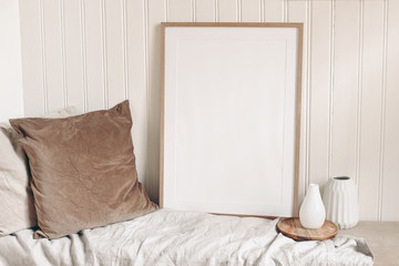 Portrait empty wooden frame mockup with linen cloth, velvet cushions and modern ceramic vases....