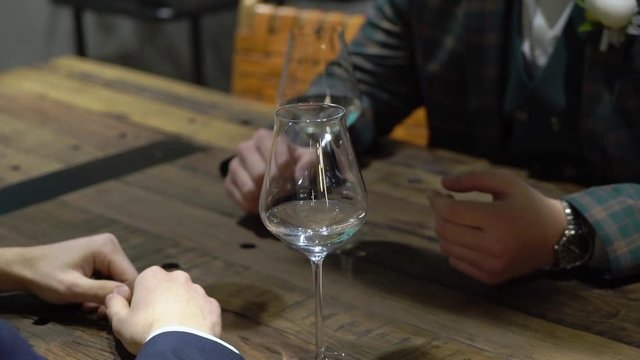 Two young men drink sitting at a table in a bar, cafe or restaurant.