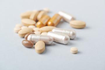 Multicolor vitamins and supplements on bright paper background. Concept for a healthy dietary supplementation. Close up. 