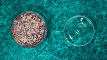 oatmeal muesli with raisins in a glass bowl on a blue background