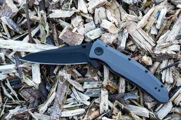 The knife is in a semi-folded position. Knife with a black blade. Sharp cutting edge.