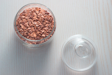 oatmeal muesli with raisins in a glass bowl on a white background