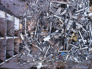 A process of buliding demolition, demolition site with heavy bulldozer and excavator with crushing equipment at work, demolished house, shot from air with drone