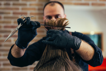 Close-up of man haircut, master does the hair styling in barber shop.