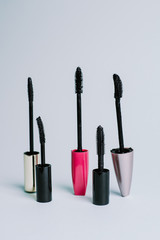 Various mascara brushes on a blue pastel background. The concept of choosing makeup products