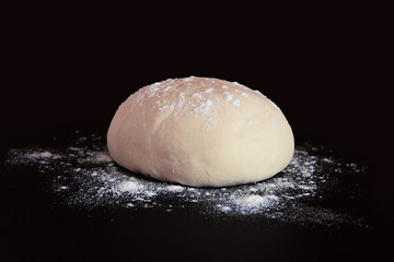 Yeast dough with flour on a dark background