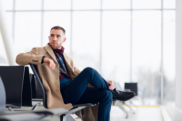 Businessman sitting at airport waiting lounge and waiting for flight. Male executive in airport business lounge sitting at waiting area.