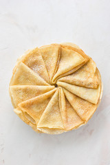Russian pancakes (crepes) with powdered sugar - traditional Maslenitsa (Shrovetide) meal on white background. Top view, copy space.