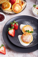 Cottage cheese pancakes with sour cream and strawberries. Traditional Russian cuisine. 