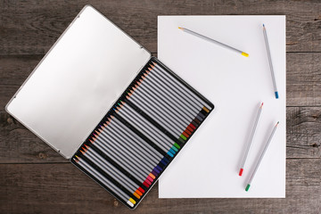 Color pencils in case and blank paper on wooden table