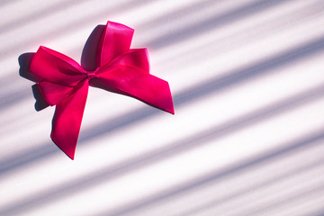 Pink bow on striped background. Gift, celebration concept