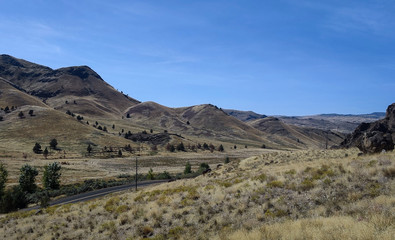 Fantastic badlands in a desert like landscape with sagebrush and a blue sky in the John Day Fossil Beds Clarno unit in Oregon