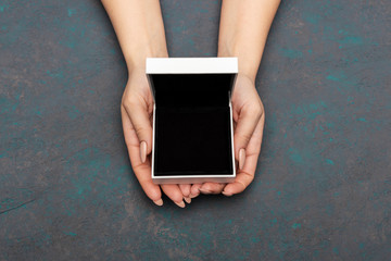 Female hands holding open white gift box top view. wedding ring presentation mock up.