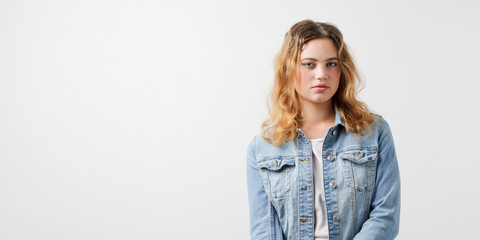 Half-length portrait of candid young European girl in a denim jacket against white background. Studio portrait