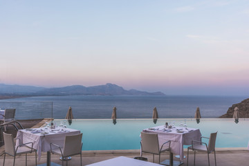 Beautiful sea view by an infinity pool deck during the blue hour.