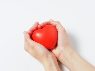 red heart in women's hands isolated on a white background. Concept of charity, health, and love