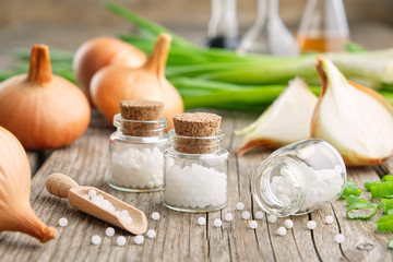 Bottles of homeopathic globules, onion bulbs and fresh green onions. Allium cepa homeopathic...
