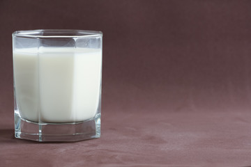 Glass beaker with milk on brown background. Copy space for your text. Plant based milk concept.