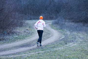 Beautiful sporty girl goes running in the forest Early spring Cold weather