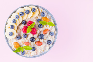 Healthy breakfast. Bowl of oatmeal porridge with fresh blueberries, raspberries, almonds and banana. Clean eating, dieting, detox, vegetarian food concept. Healthy lifestyle concept
