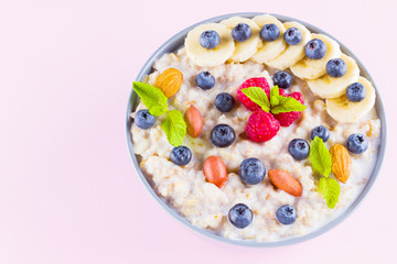 Healthy breakfast. Bowl of oatmeal porridge with fresh blueberries, raspberries, almonds and banana. Clean eating, dieting, detox, vegetarian food concept. Healthy lifestyle concept
