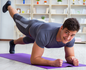 Young man exercising at home in sports and healthy lifestyle con