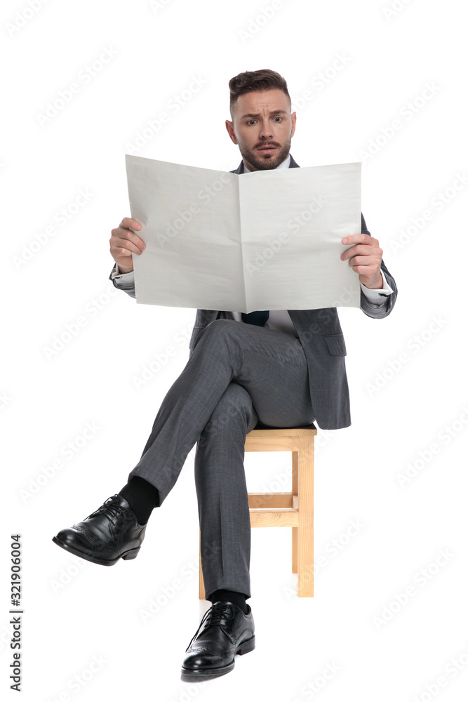 Poster shocked young businessman reading newspaper