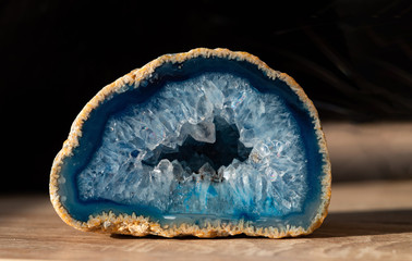 Geode with transparent crystals of light-blue color on a dark background..